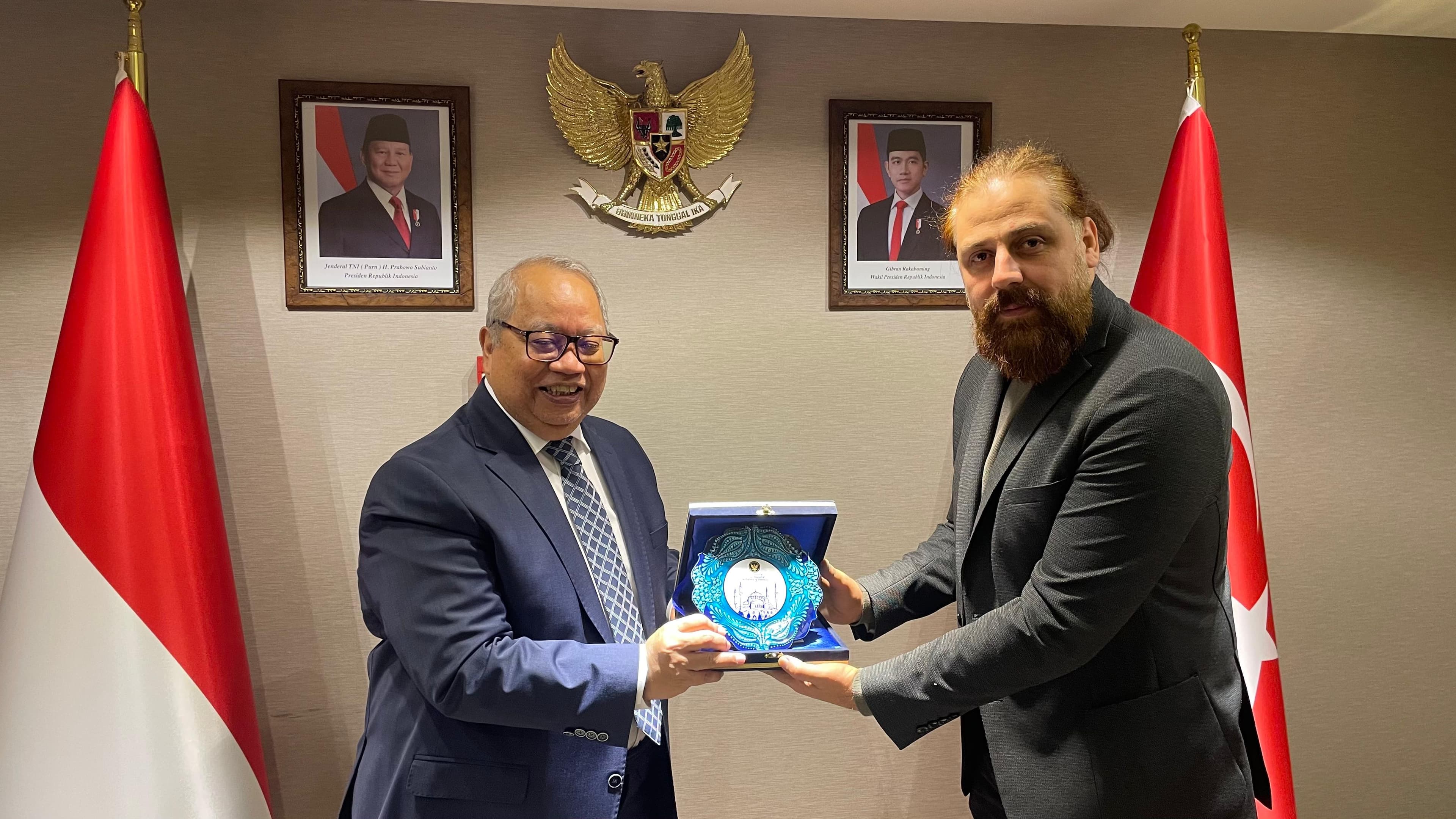 Kurumsal temsilcilerin bayraklar önünde iş birliği plaketi takdim ettiği an