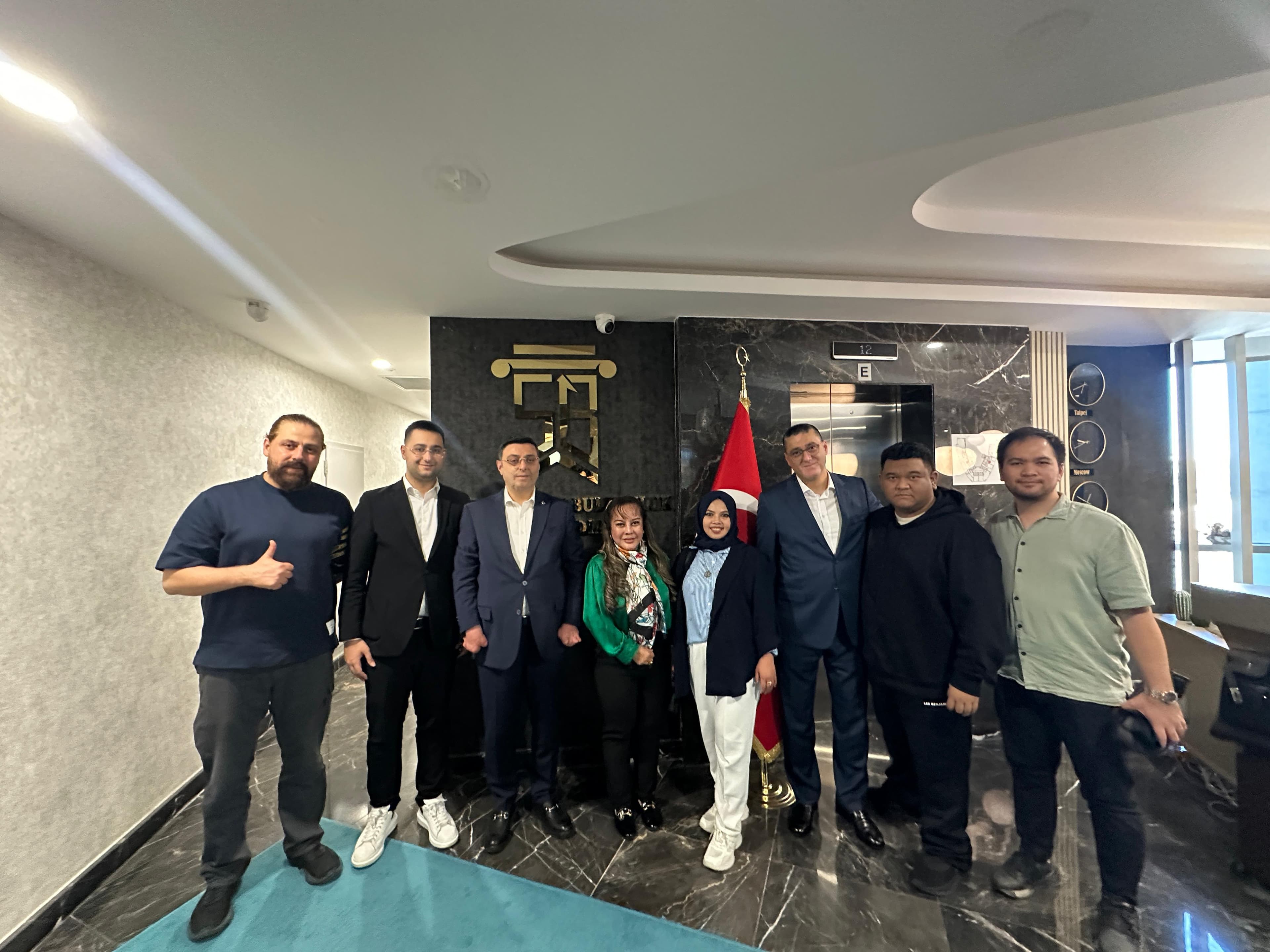 Kurumsal temsilcilerin modern lobi alanında saha temasları sonrası verdiği grup fotoğrafı